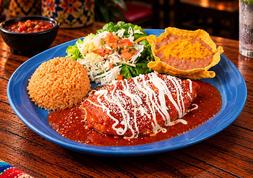 A blue plate with a sauced entr&eacute;e topped with crema and cheese, Mexican rice, salad with pico de gallo and refried beans in a tortilla cup, with salsa on the side