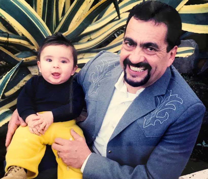 Jose “Pepe” Ramos smiling and holding a baby